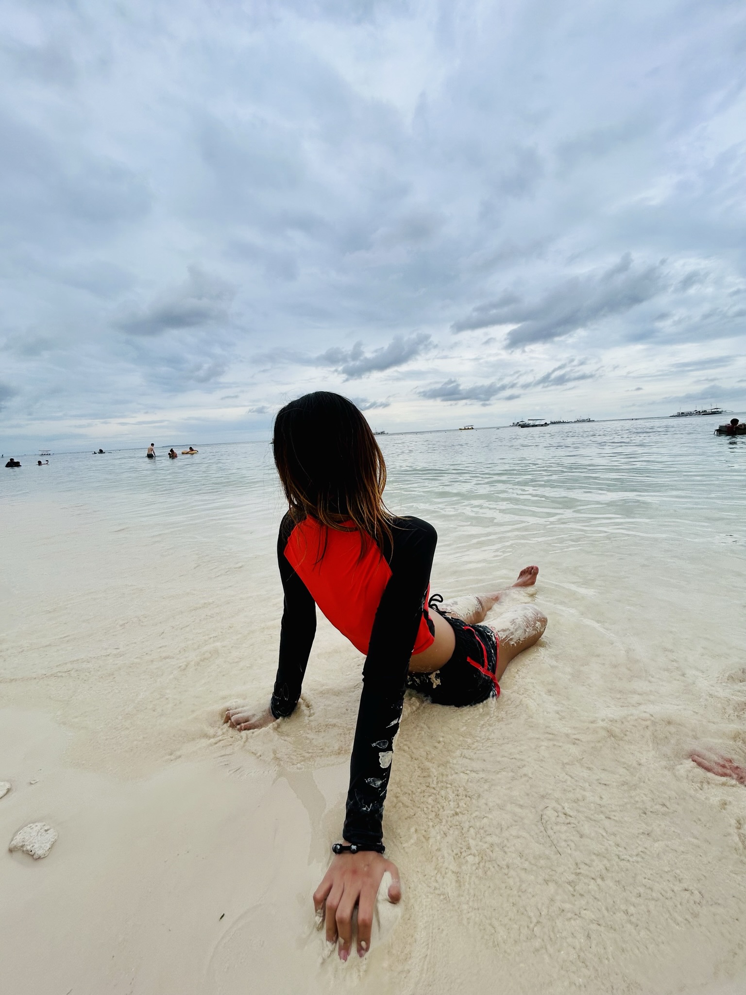 Woman wearing an orange swimsuit sitting at the beach.