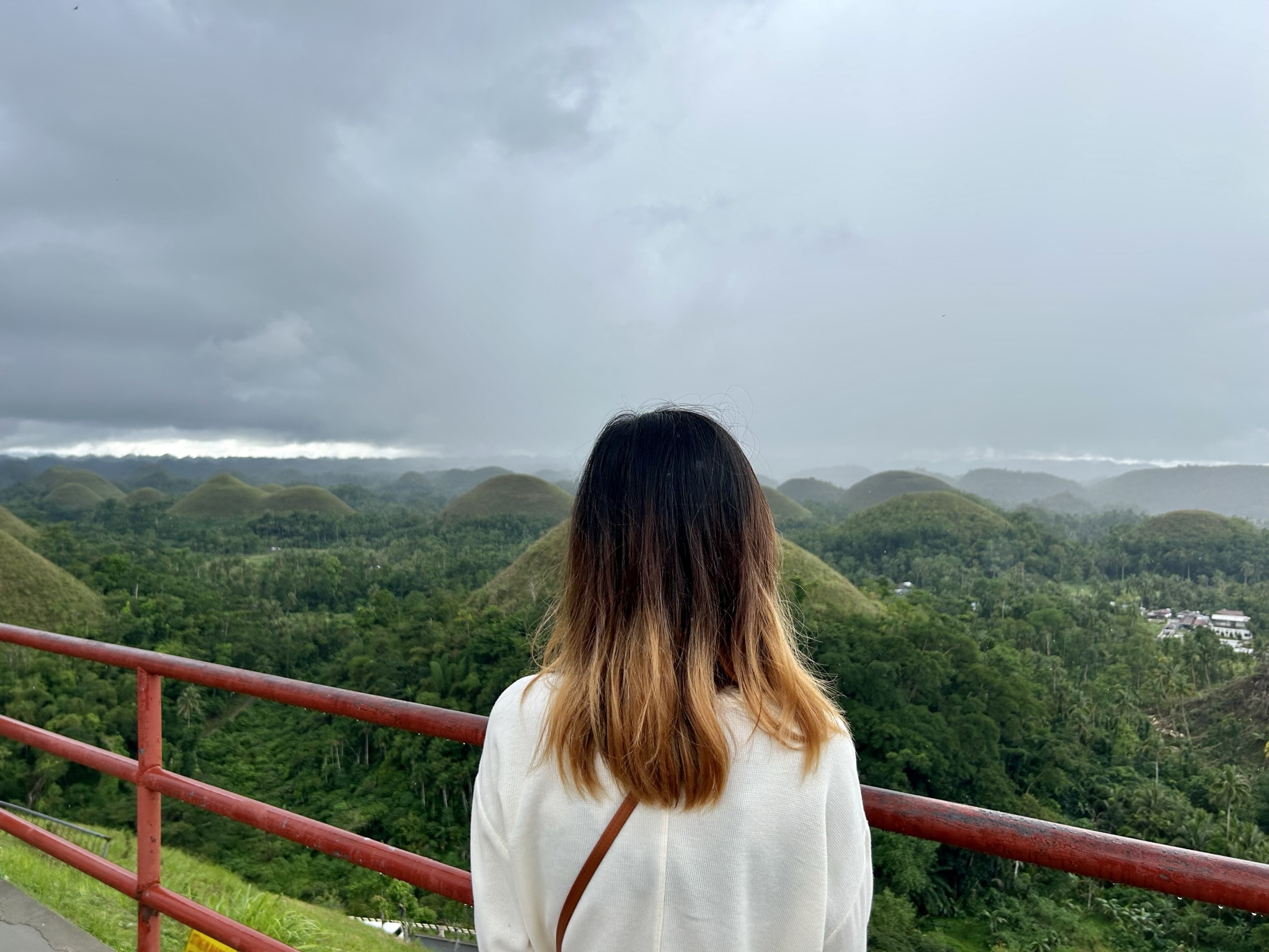 Back of the woman that is facing the chocolate hills.